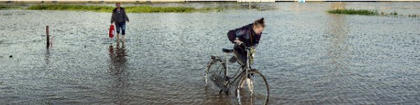 fietser en voetganger lopen door hoog water