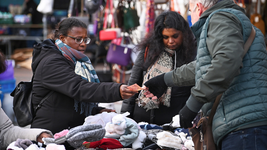 Vrouw koopt warme sokken op de markt, ze betaalt met contant geld