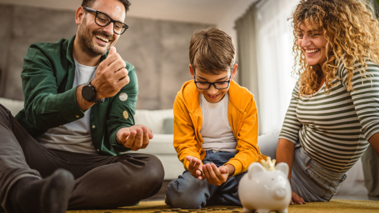 Moeder, vader en zoon zitten op het tapijt en sparen geld in de spaarpot.